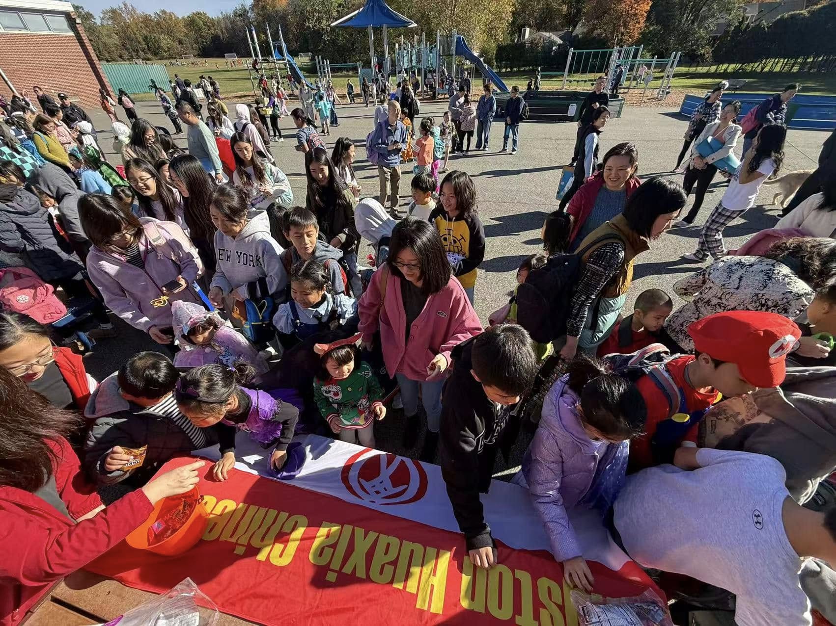Livingston Huaxia Chinese School Volunteer Club activity booth with families and student volunteers.